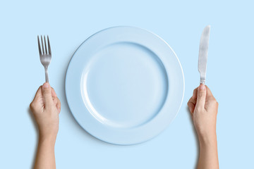 Blue plate with silver fork and knife on blue background with clipping path.