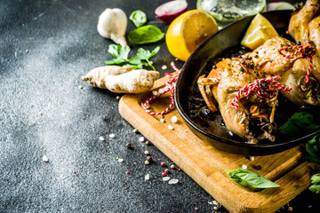 Delicious fried roasted quails with herbs, spices and greens. Grilled quails carcasses in a baking dish. Holiday Christmas and Thanksgiving meal concept.