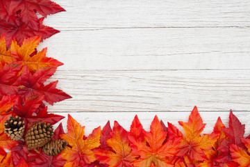 Naklejka na ściany i meble Red and orange fall leaves and pine cones on weathered whitewash wood textured background
