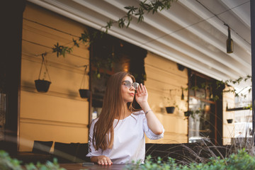 Attractive young girl in glasses sits at a restaurant table