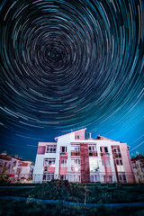 Circle star trails in the night sky above the suburb houses