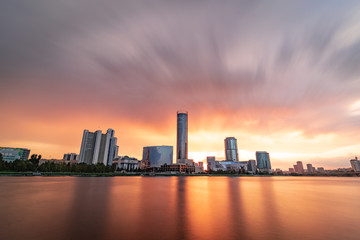 Fototapeta premium Beautiful cloudy sunset at the city pond. Long Exposure cityscape of Yekaterinburg, Russia with skyscrappers reflecting in water
