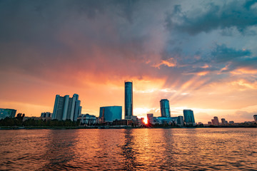 Beautiful cloudy sunset at the city pond. Cityscape of Yekaterinburg, Russia with skyscrappers reflecting in water