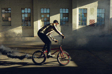 BMX rider in an empty warehouse using smoke grenade