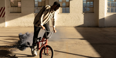 BMX rider in an empty warehouse using smoke grenade