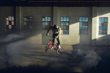 BMX rider in an empty warehouse using smoke grenade
