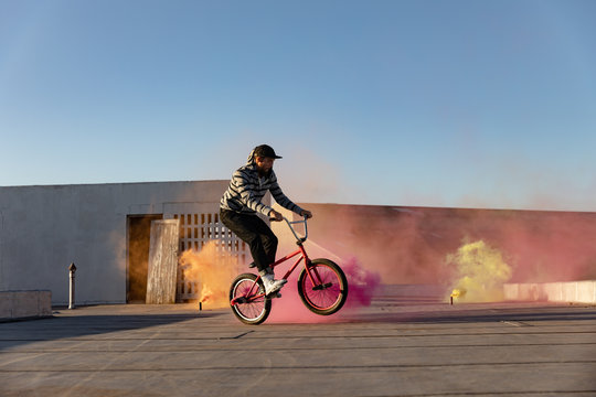 BMX rider on a rooftop using smoke grenades - Powered by Adobe