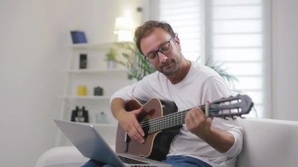 Man playing acoustic guitar in the living room.