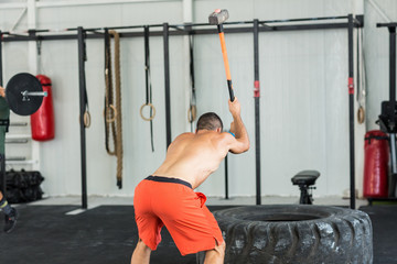Fototapeta premium Sport fitness man hitting tractor tire with a sledgehammer