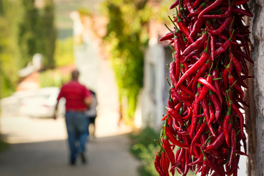 Drying long red pepper with hanging in shadow. An old man walking in background in Cukuroren Village, Bilecik / Turkey
