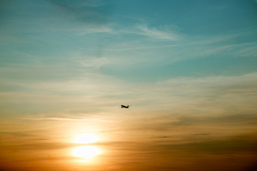 Commercial airplane flying above clouds in dramatic sunset light