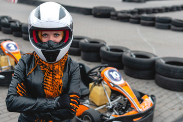 Portrait of a pretty girl wearing a white helmet close up, detail of Go-kart. karting track racing, copy space. serious look, determination, active lifestyle, extreme sport