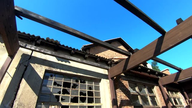 4K Left pan tilt down abandoned building with broken windows and wooden pergola