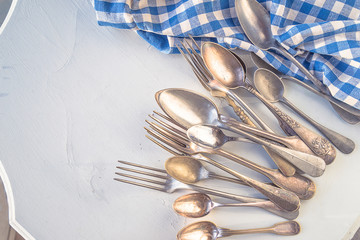 A lot of vintage forks and spoons, checkered napkin on the white paint rustic background