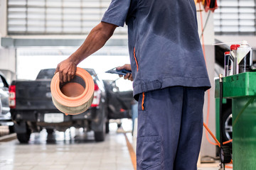 Auto mechanic using the blower to clean the car air filter.