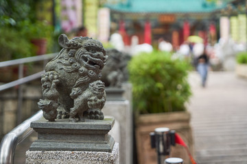 stone lion sculpture in front of temple in hong kong