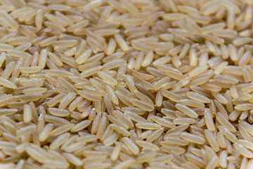 Raw long uncooked brown rice grains background