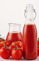 Tasty Tomato juice in a glass with ripe red tomatoes on white background,