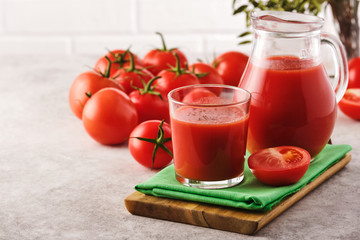 Tasty Tomato juice in a glass with ripe red tomatoes.