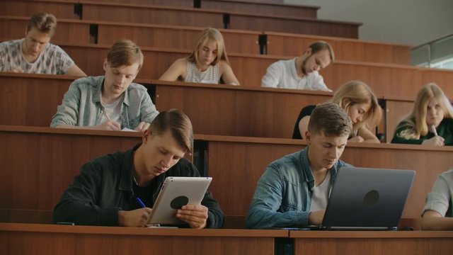Large Group of Multi Ethnic Students Working on the Laptops while Listening to a Lecture in the Modern Classroom. Bright Young People Study at University