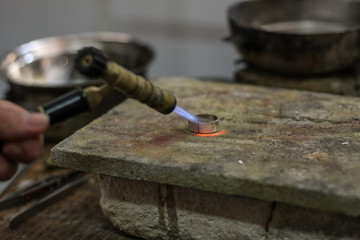 A jewelry master is working to create a silver ring