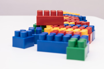 On a white background in a chaotic manner are large multi-colored childrens blocks-designer for the construction of houses and buildings of varying complexity. copy space.
