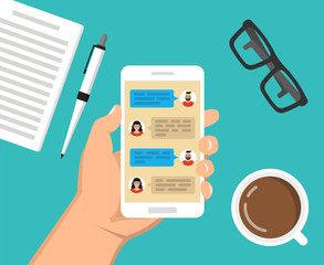 Hand holding smartphone with text messaging on the screen. Сup of coffee, notebook with pen and glasses lay on the table. Vector flat illustration.
