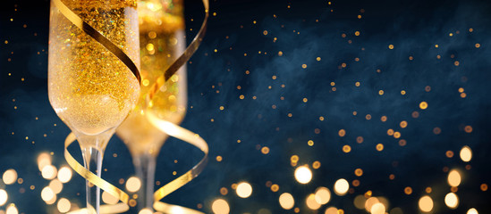 Fototapeta Two glasses of champagne with golden confetti, glitter, serpentine and lights. obraz