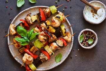 Barbecue of chicken on skewers with vegetables on stone background. Picnic.