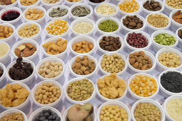 Cereal grains, seeds, beans on white plastic plate.