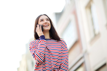 beautiful young woman smiling outside and talking with cellphone