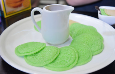 Green sweet pancakes made from flour with sweet sauce on white plate.