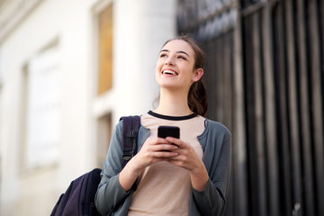 happy young woman holding mobile phone and looking away