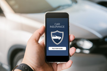 Male hand holding smartphone with car insurance concept.