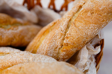 three fresh baguettes lie in a wicker basket