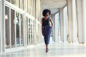 A young fashionable Afro-American woman confidently walking down the hall outside the financial building