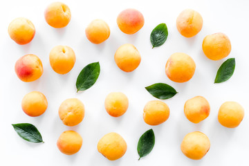 Apricots and leaves pattern on white top view