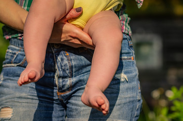 Bare legs of a young child on a parent hand closeup