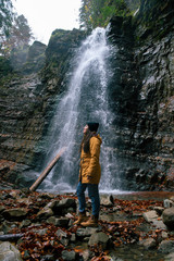 woman near waterfall in forest autumn season