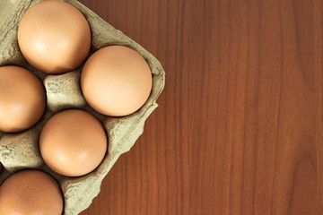 Fresh brown organic eggs in grocery package close up on wood table background