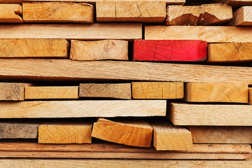 Sawn and folded boards with an emphasis on one red board, construction boards, full-screen lumber...