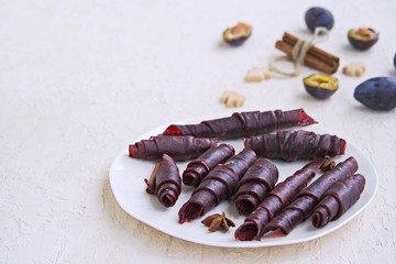 Pastille, handmade natural sweet apple and plum puree, rolled into rolls, on a white plate. Healthy desserts. Harvest apples and plums. Thanksgiving Day. Selective focus