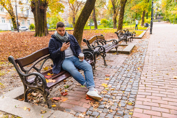 man drinking coffee outdoors autumn season talking on the phone