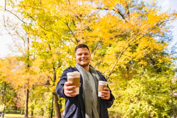 man brings coffee to friend drink to go outdoors autumn city park