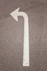 Wei&szlig;er Pfeil auf Stra&szlig;e zeigt abbiegen. Road sign arrow Indicating left turn.