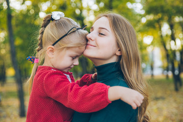 mather with little toddle daughter playing in autumn city public park