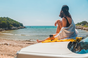 happy woman at sea summer beach sitting at car hood