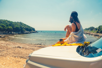 happy woman at sea summer beach sitting at car hood