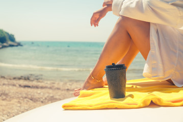 woman legs with coffee cup at car hood
