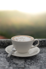 A cup of coffee put on table with mountains background
